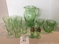 Full set of green Depression glass items including pitcher, teacups, bowls, small glasses, and salt and pepper shakers.