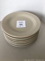Stack of 8 cream-colored Pottery Barn dinner plates showing raised dot border detail