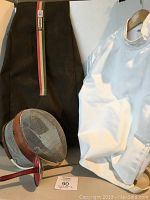 Fencing jacket size 42, fencing mask with metal mesh and leather trim strap, and Santelli branded black and beige carrying bag with stripe detail.