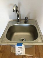 Front angle view of stainless steel bar/prep sink fitted with chrome Delta faucet with tall curved spout and single lever handle. Shows basin and outer rim with drain.