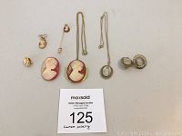 Lot display including two necklaces, two pairs of clip-on earrings, two pins, and single clip-on earrings arranged on table.