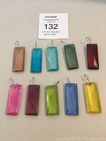 Top-down image showing ten rectangular faceted glass pieces in various colors laid out on a flat surface.