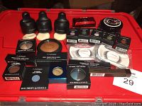 Overview of the lot showing MAC liquid foundations, eyeshadows, pigments, false eyelashes, lipstick compact, and Hello Kitty cosmetic powder.