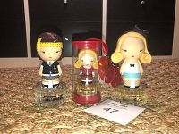 Photo showing all three collectible Harajuku Lovers perfume bottles arranged on a textured surface, with distinct character designs and bases including labels.