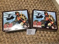Two GI Joe Action Marine lunch boxes side by side on carpet with plastic film seal visible