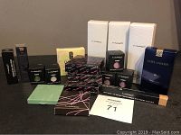 Photo showing multiple boxed MAC cosmetic products including pigments and pressed powders along with Estee Lauder boxed powder blush.