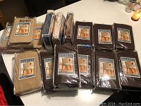 Photo of 14 new packaged chair covers in beige, brown, and black colors laid on flat surface