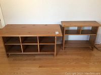 Two solid wood tables against a wall, larger table with multiple compartments on the left, smaller side table with compartments on the right.