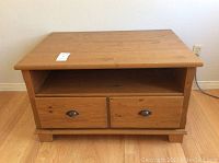 Front view of solid wood storage table showing two drawers with metal handles and open back storage space.