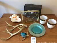 Lot contents on wooden surface, showing all items including Umbra picture frame with box, decorative antlers, blue turtle, cups, plate and ghost dish.