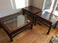 Coffee table on left with two end tables on right beside window on hardwood floor