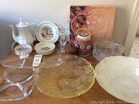 Full view of assorted glassware, ceramics including teapot, serving plates, decorative jar, crystal bowl with visible chip