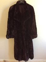 Front view of the dark burgundy shear beaver fur coat hanging on hanger showing wide lapel collar and cuffed sleeves.
