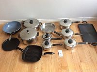 Full set of 10 assorted pots and pans including fry pans, saucepans, grill and griddle pans on wooden floor.