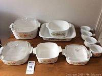 All CorningWare baking dishes and Hearth Side Bake N' Serve bowls displayed on table, showing lids and floral patterns.