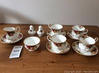 Full set arranged on table showing 4 teacups, 5 saucers, creamer, salt and pepper shakers, and small dish with floral pattern.