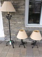 Set includes one 58-inch tall floor lamp and two 26-inch tall table lamps against a brick wall background, showing lamps' bases and shades.