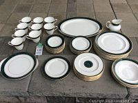 Full overview of set displayed outdoors showing cups, saucers, plates, bowls, creamer, serving dishes