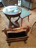 Photo showing all three items: circular glass top table with carved wooden base, rectangular mosaic tile table, and solid wood magazine holder in front.