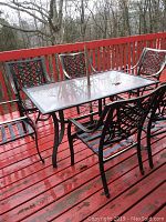 Rectangular glass-top table and six metal chairs on deck