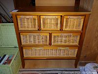 Front view of a wooden storage unit with six wicker basket drawers.