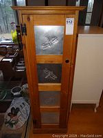 Front view of closed cabinet showing door with embossed dragonfly panels