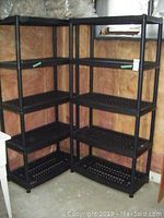 Four black resin shelving units with grid shelves arranged in a corner, showing overall size and appearance.