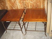 Pair of square end tables seen from above showing wooden tops and metal bases with grid shelves below.