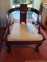 Front view of Asian inspired wooden chair with cushion on seat, showing curved arms and claw-foot legs
