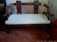 Front view of wooden Asian inspired settee with white cushion seat.