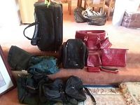 Wide angle photo showing the assortment of black rolling duffel, green travel bags, and red women's handbags.