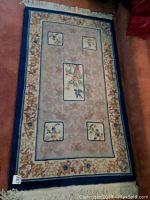 Full view of the 5.75ft x 3ft area rug showing the floral and bird design and the border.