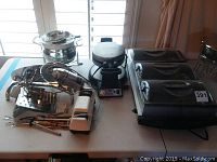 Overview of buffet server, meat slicer, knife sharpener, knives, and waffle iron on table.