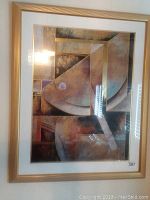 Front view of framed abstract geometric wall art painting with visible light reflection on glass.