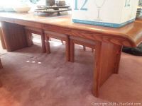 Side angle of oak dining table showing thick rectangular top and two vertical panel legs