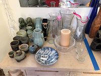 Overview of the collection on table including ceramic and glass art pieces with candle and plate