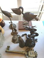 Various metal bird figurines including flamingo, swan, a dragon sculpture, and a large brass key