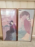 Pair of two framed Asian-inspired wall art prints leaning against a white wooden panel wall showing both prints and frames.