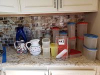 Overview of all plastic storage containers with lids and pitchers on kitchen counter