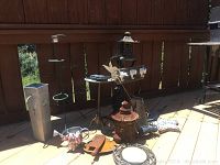Full view of entire collection of outdoor metal garden art displayed together showing various items with rust patina on wood deck and fence background.