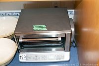 Front view of Cuisinart toaster oven showing stainless steel body, glass door, and digital control panel with labeled cooking settings and buttons.