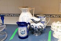 Photo of all four blue and white jugs on a kitchen counter, showing variety of styles and sizes