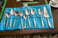 Overview of all flatware pieces and storage pouches laid on turquoise felt