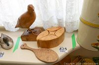 Wooden bird sculpture, five-piece box, and hand mirror together on a surface demonstrating size and grain texture.