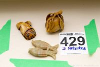 Three carved netsuke items placed on a white surface with green tape and a MaxSold tag showing lot number 429.