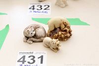 Three animal netsuke displayed on a flat surface including a curled cat, an elephant on a rock, and a small tiger or cat figure.