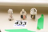 Front view of three netsuke figurines showing detailed carved faces and painted clothing