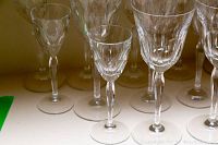 Fourteen assorted clear crystal wine glasses shown in a row highlighting different sizes and subtle etched vertical cuts on some glasses.