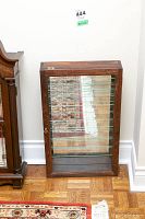 Full front view of the wood curio cabinet with glass shelves and mirrored back, showcasing overall condition and design.