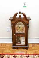 Full front view of the wooden pendulum wall clock showing overall design and proportions.